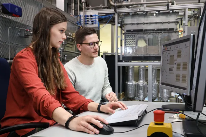 Zwei Studenten sitzen vor einem Computerbildschirm, auf dem ein Simulationsprogramm läuft